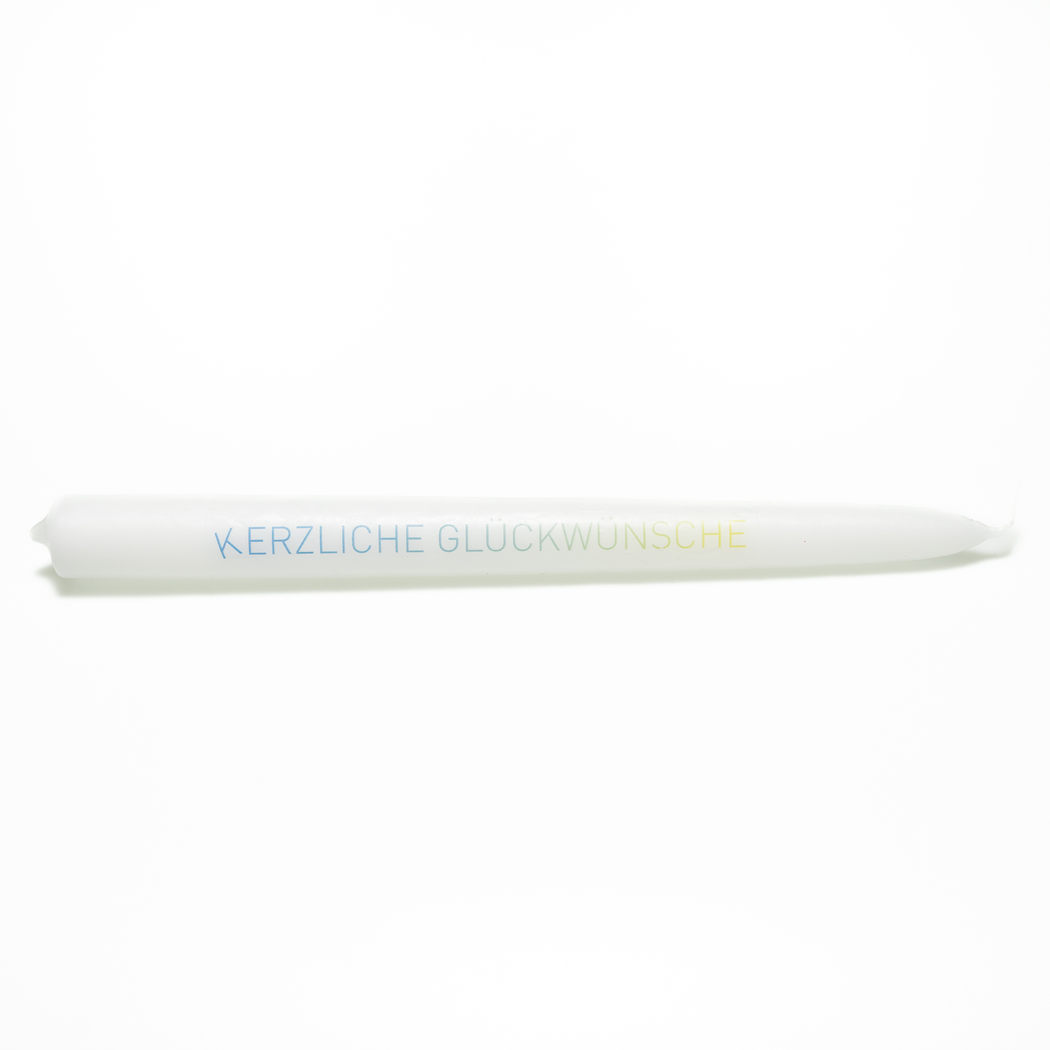 Weiße Tafelkerze mit der Aufschrift „Kerzliche Glückwünsche“ in schlichten Versalien geschrieben mit einem Farbverlauf von blau nach gelbgrün. Das „K“ steht etwas schräg.