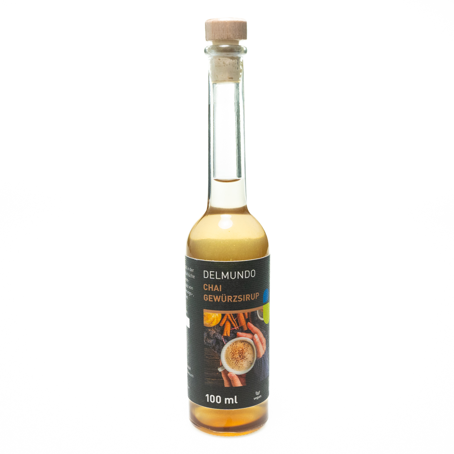 Eine klare Glasflasche mit Bügel-Verschluss gefüllt mit goldbraunem Gewürzsirup. Daneben liegen Zimtstangen und Gewürznelken.