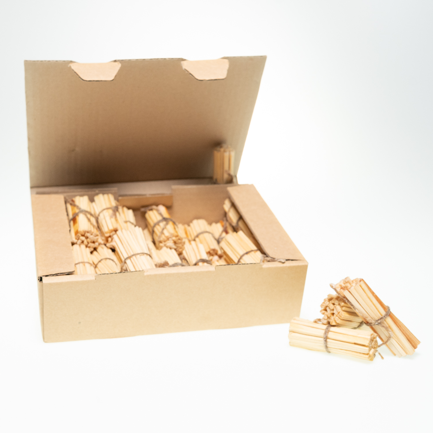 Ein offener Karton mit 40 Bündel aus dünnen Holzstäbchen, die mit einer in Wachs getränkten Kordel zusammengebunden sind.