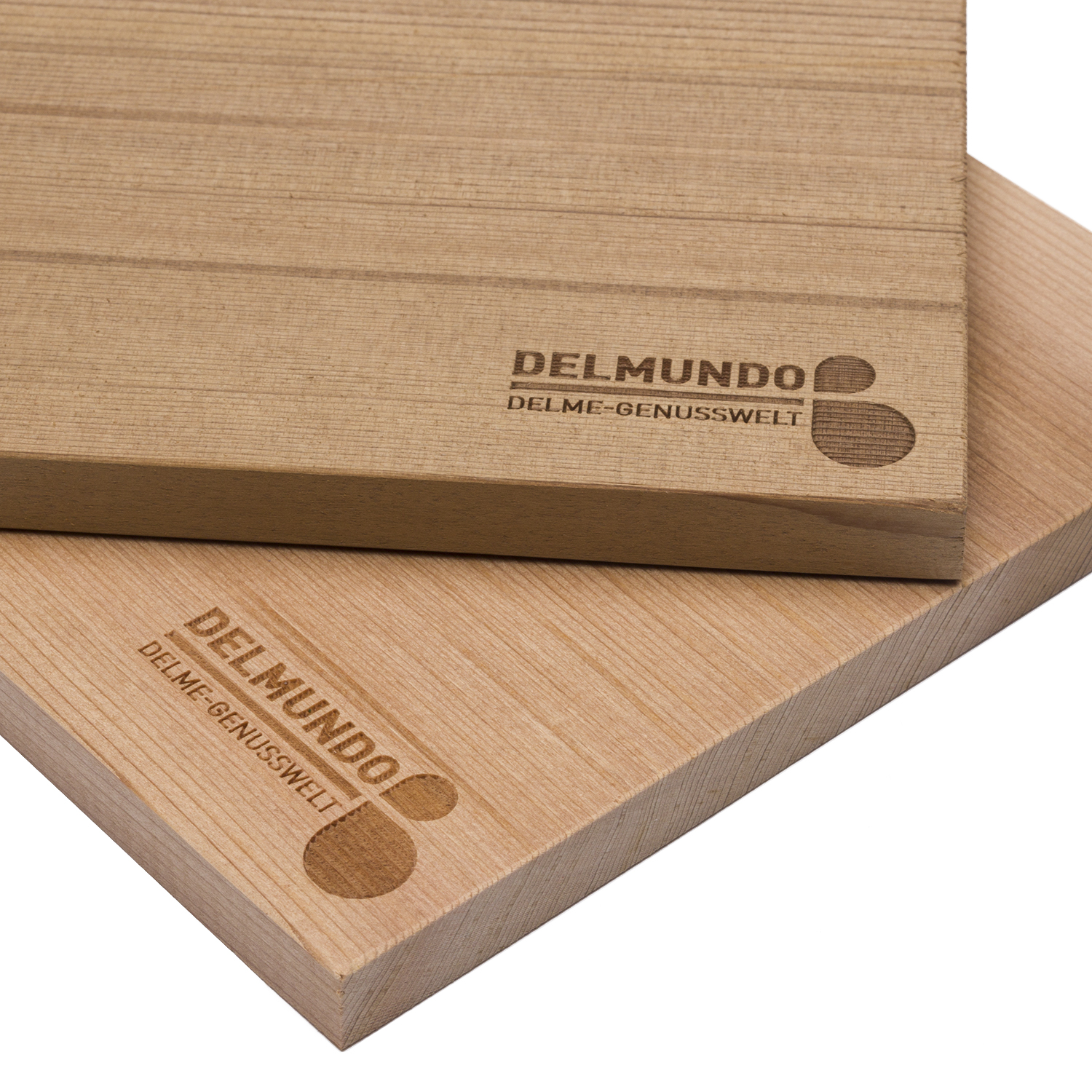 Zwei rechteckige Zedernholzbretter leiegen aufenander. In der der unteren rechten Ecke befindet sich in einem dunkleren Braun als das Holz der Schriftzug "DELMUNDO – DELME-GENUSSWELT".