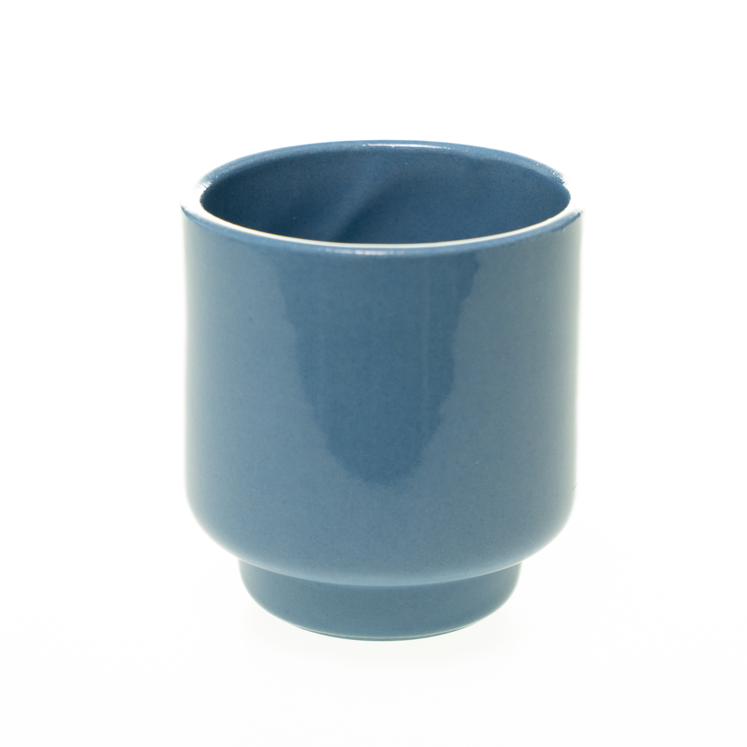 Schlichter, zylindrischer Keramikbecher in blau mit glatter Oberfläche. Der untere Rand ist leicht zurückgesetzt.