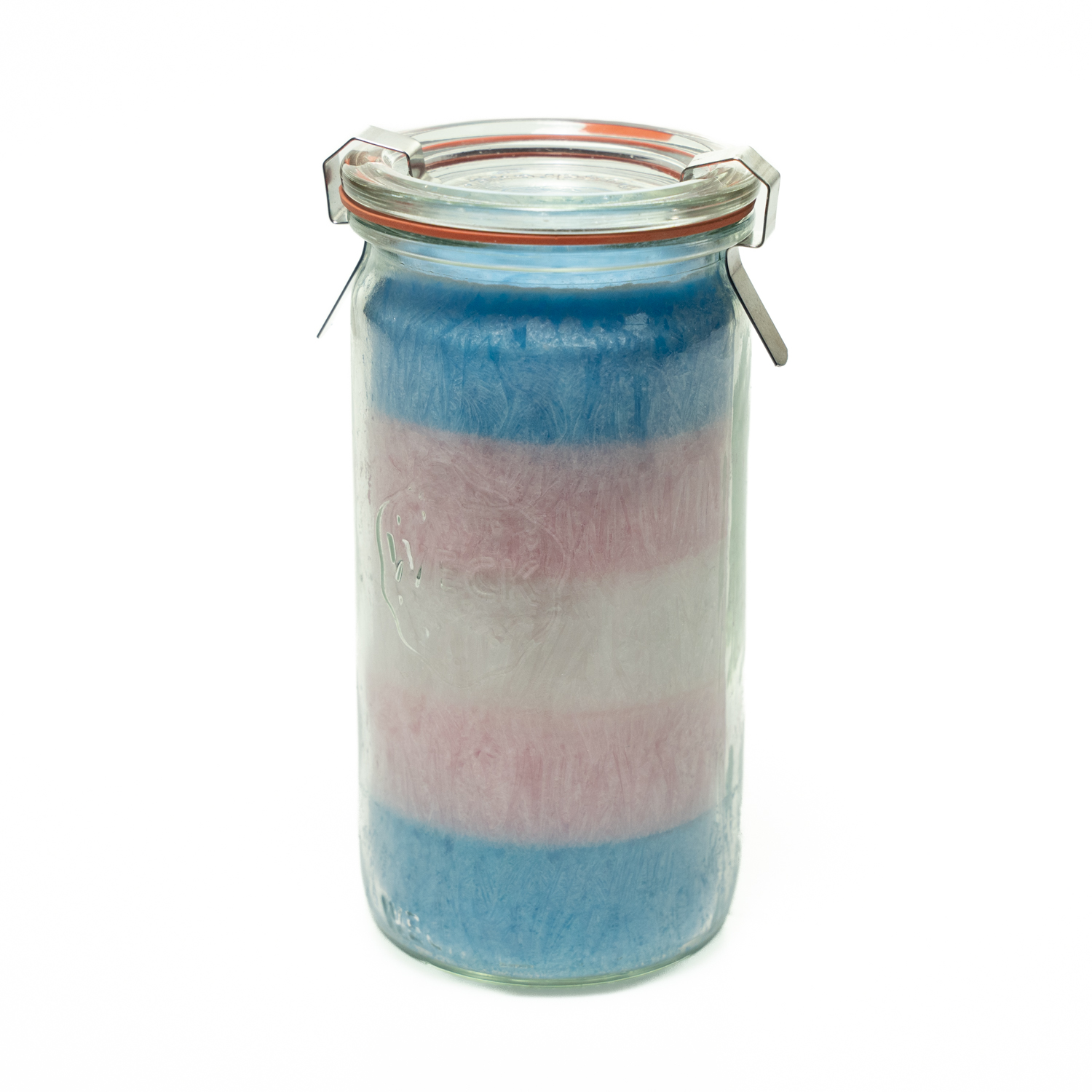 Kristallkerze in einem schlanken, runden, hohen und durchsichtigem Einmachglas. Das Wachs ist in den Farben der Transflagge von unten nach oben in den Farben hellblau, rosa, weiß, rosa, hellblau geschichtet