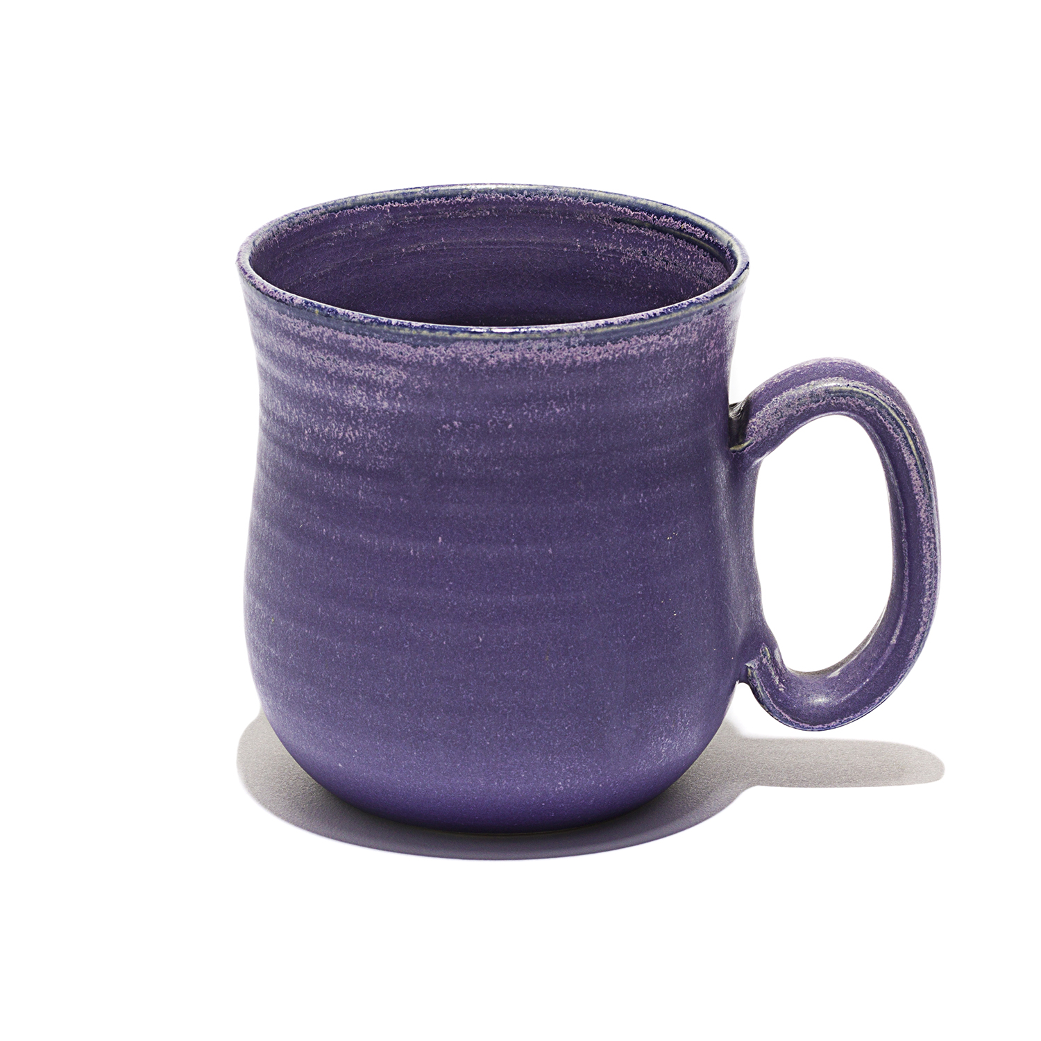 Eine bauchige Tasse in einem kräftigem lila glasiert. Am Rand des Griffes und dem Tassenrand, ist die Glasur leicht durchscheinend.