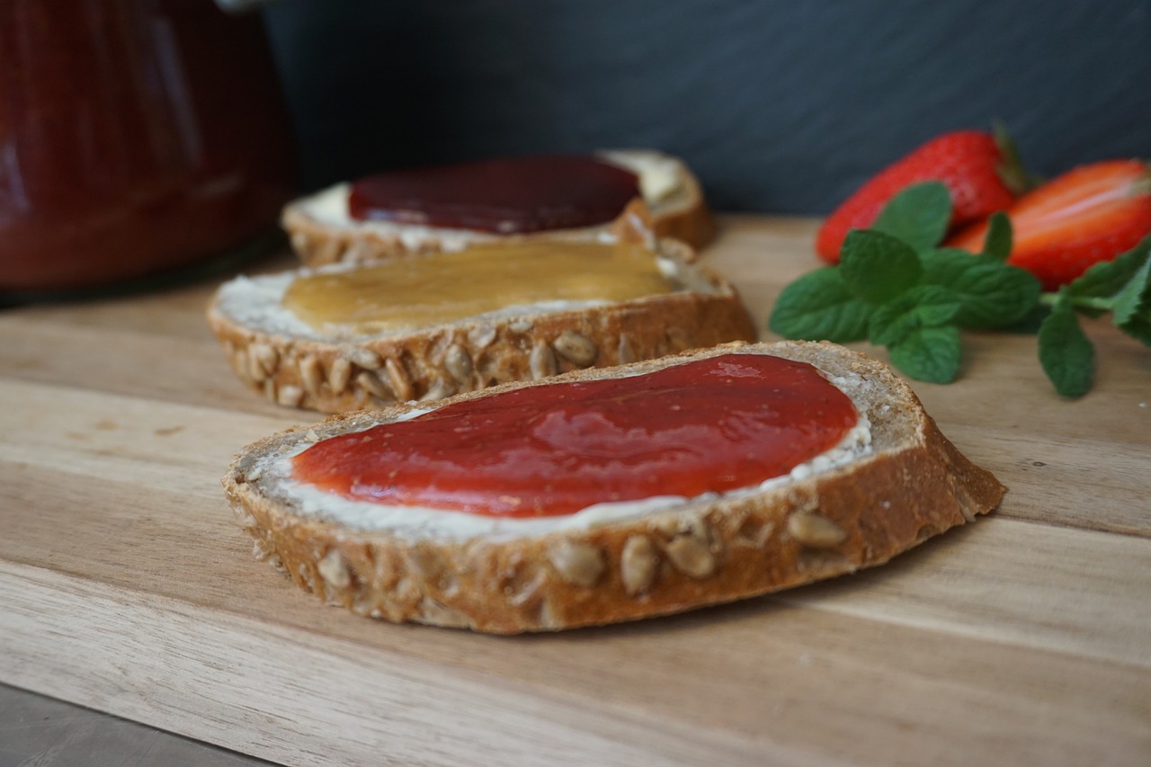 Drei scheiben Brot mit Fruchtaufstrich auf einem Holzbrett
