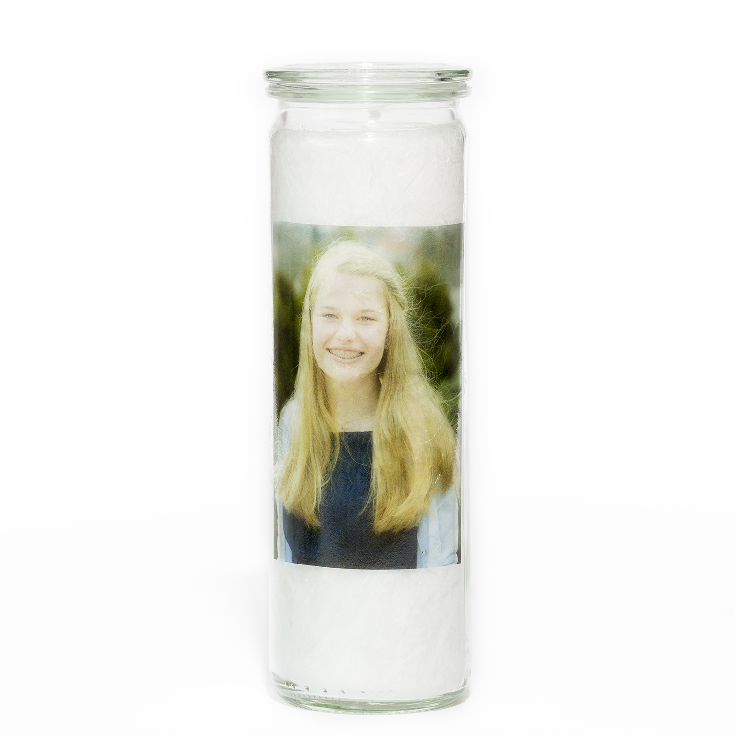 Weiße Kristallkerze in einem schlanken, runden, hohen und durchsichtigem Einmachglas. Auf dem weißen Wachs ist durch das Glas das Foto eines Mädchens zu sehen.