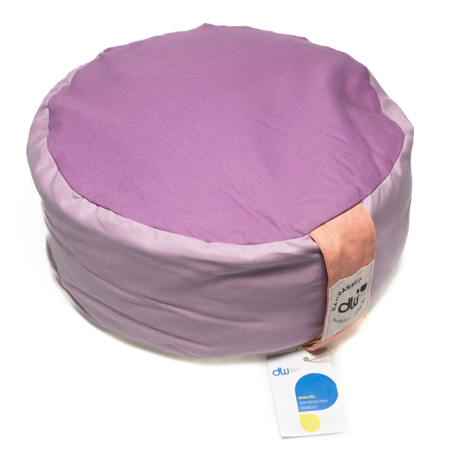 Rundes Yogasitzkissen. Die Seite ist lila oben und unten ist der Stoff fliederfarben. An der Seite ist eine Stofflasche in der Farbe rosé zum Tragen und der Bezug kann mit einem Reißverschluss geöffnet werden.