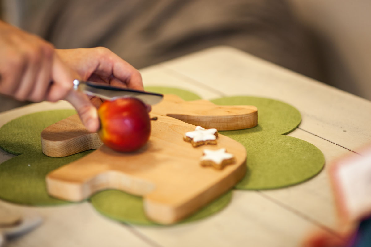 Ein Apfel wird auf einem Brettchen in Tierform geschnitten