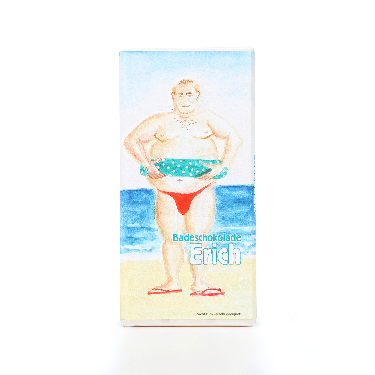 Cremeweißer Badezusatz in Schokoladenform. Auf der Packung der Badeschokolade ist ein gemalter Mann mit roter Badehose am Meer abgebildet.