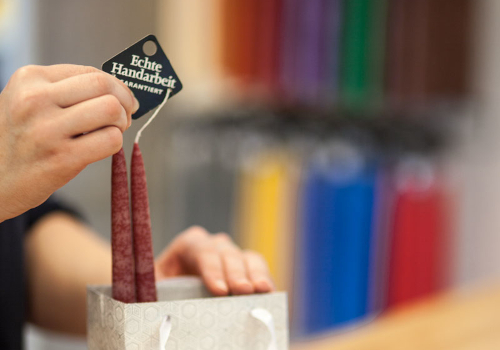 Dunkelrote Tafelkerzen, die gerade in eine Tüte gepackt werden