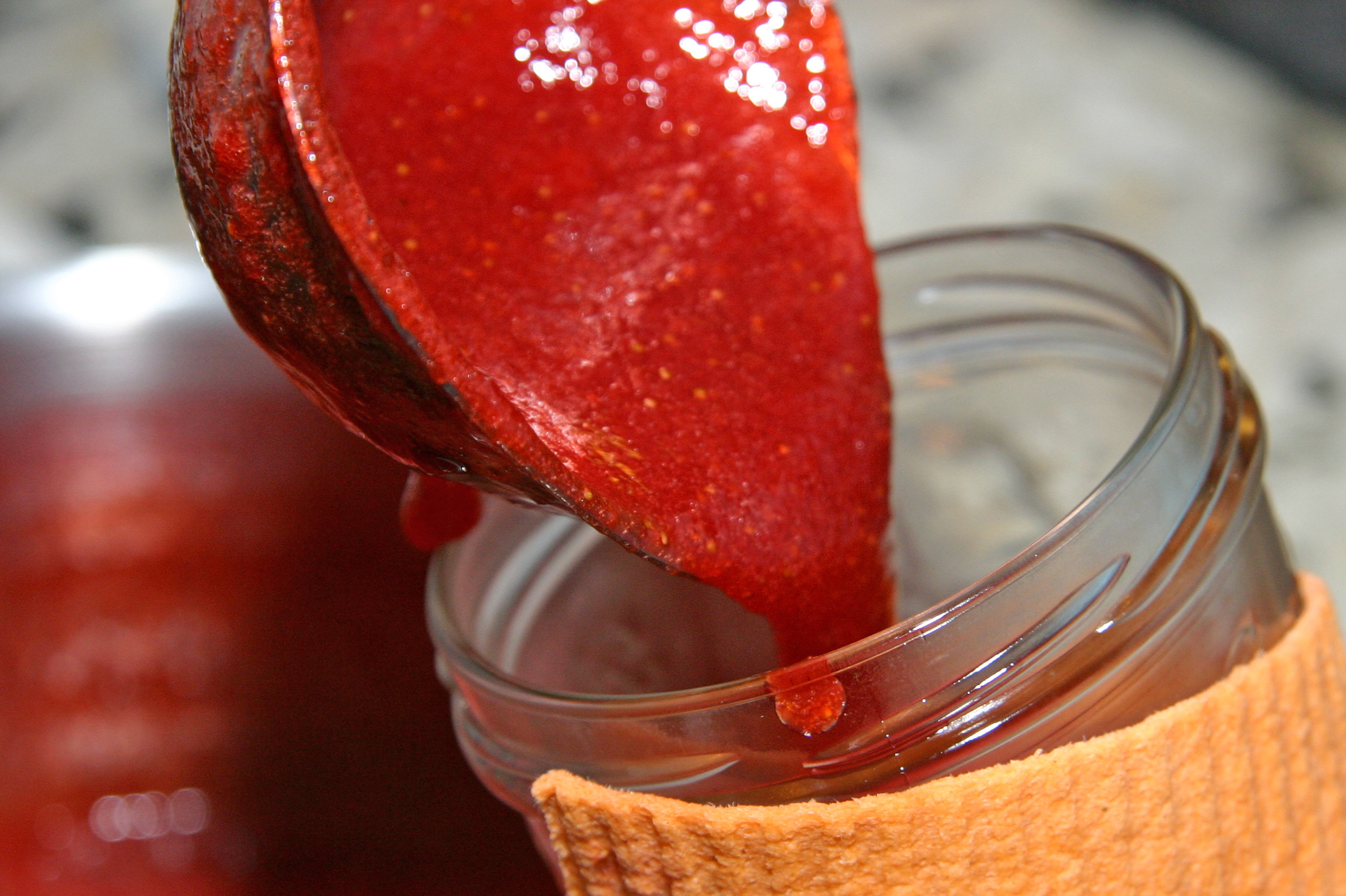 Roter Fruchtaufstrich, der gerade in ein Glas gefüllt wird
