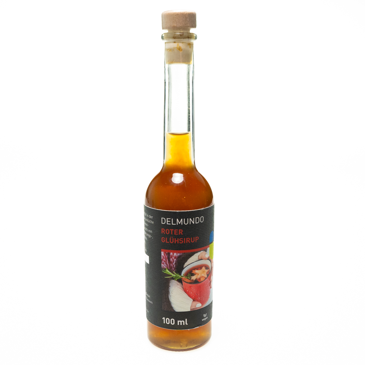 Eine klare Glasflasche mit Bügel-Verschluss gefüllt mit kräftig rot-braunem Glühsirup. Daneben liegen Zimtstangen und Gewürznelken.